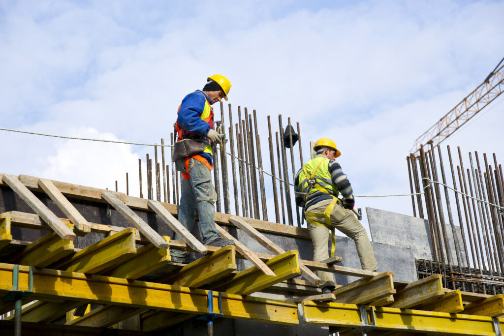 Dois homens trabalhando em uma obra enquanto usam EPCs.